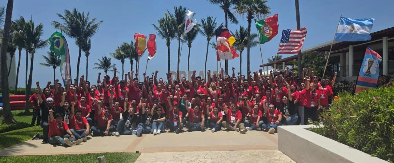 Grupo corporativo completo celebrando con banderas durante la experiencia Mundial de TEAMS en un hotel de Cancún